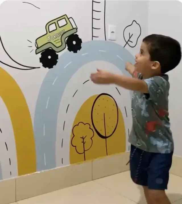 Menino animado diante de um mural de estrada com jipe